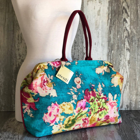 Floral patterned handbag with teal blue background and floral design.
