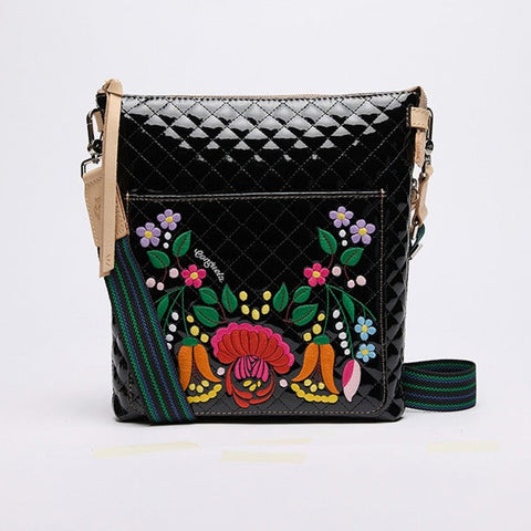 Black quilted handbag with colorful floral embroidery on a bright background