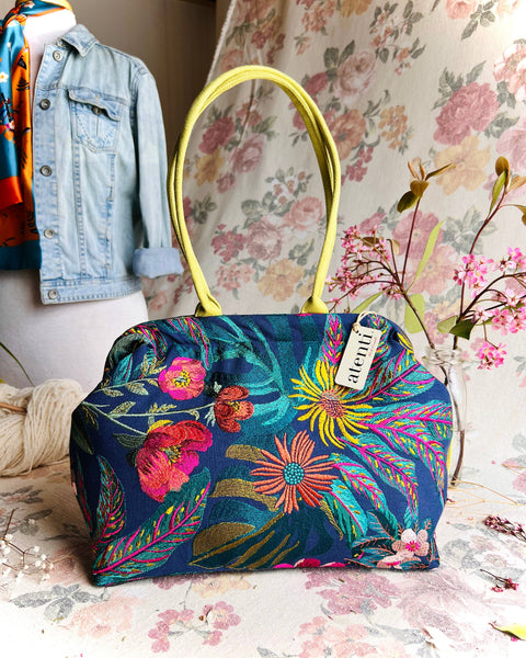 Colorful navy based floral-patterned handbag on a floral background.