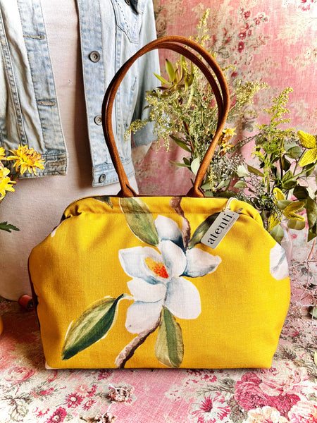 Yellow handbag with white floral magnolia design.