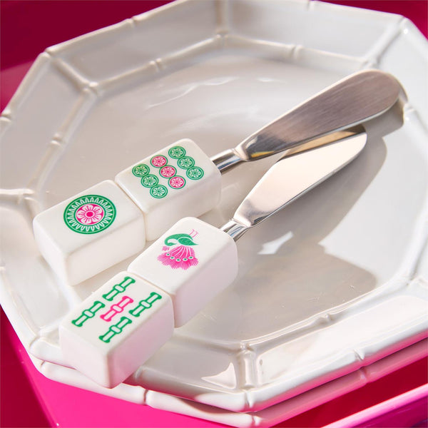 Two white rectangular blocks with pink and green mahjong tile designs on a white plate with a silver knife.