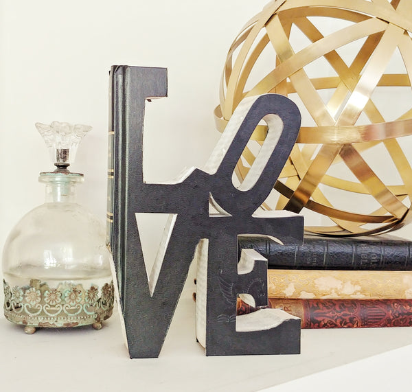 Vintage Book that has been cutout into the word LOVE sitting on a bookshelf as decor.